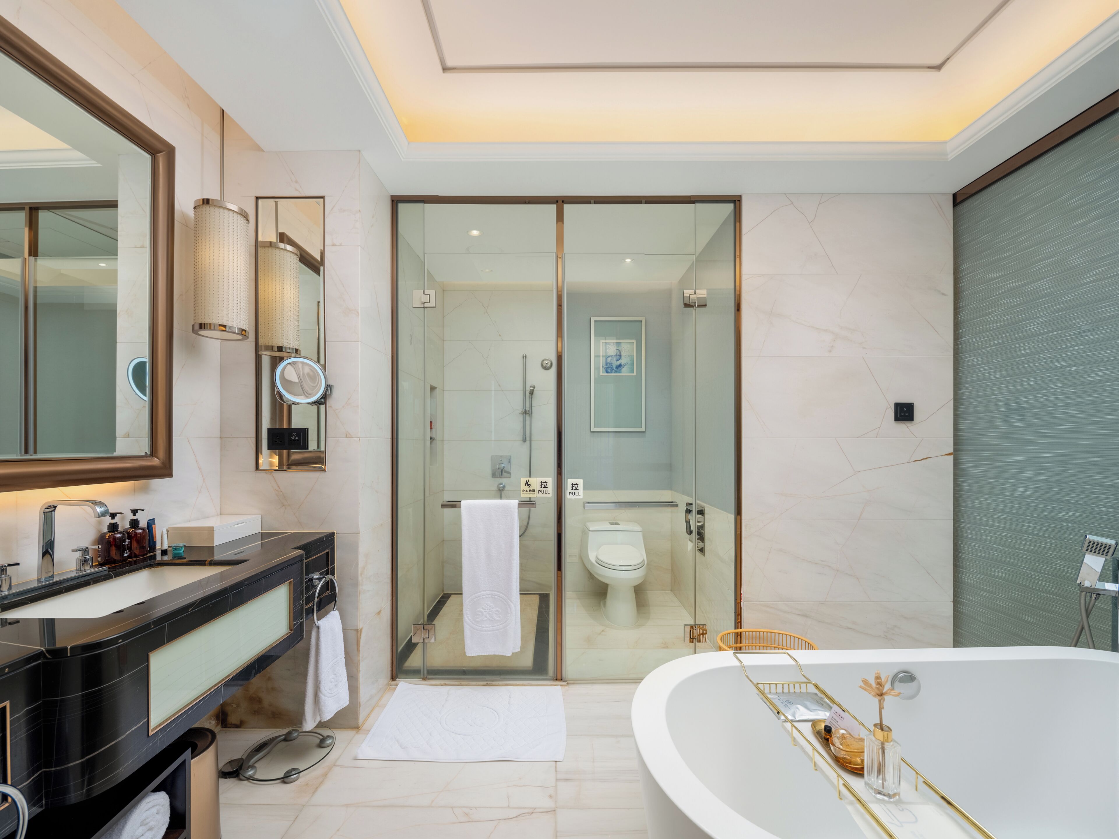 Un baño moderno con una bañera grande, una ducha con mampara de vidrio y un tocador con espejo y lavabo.