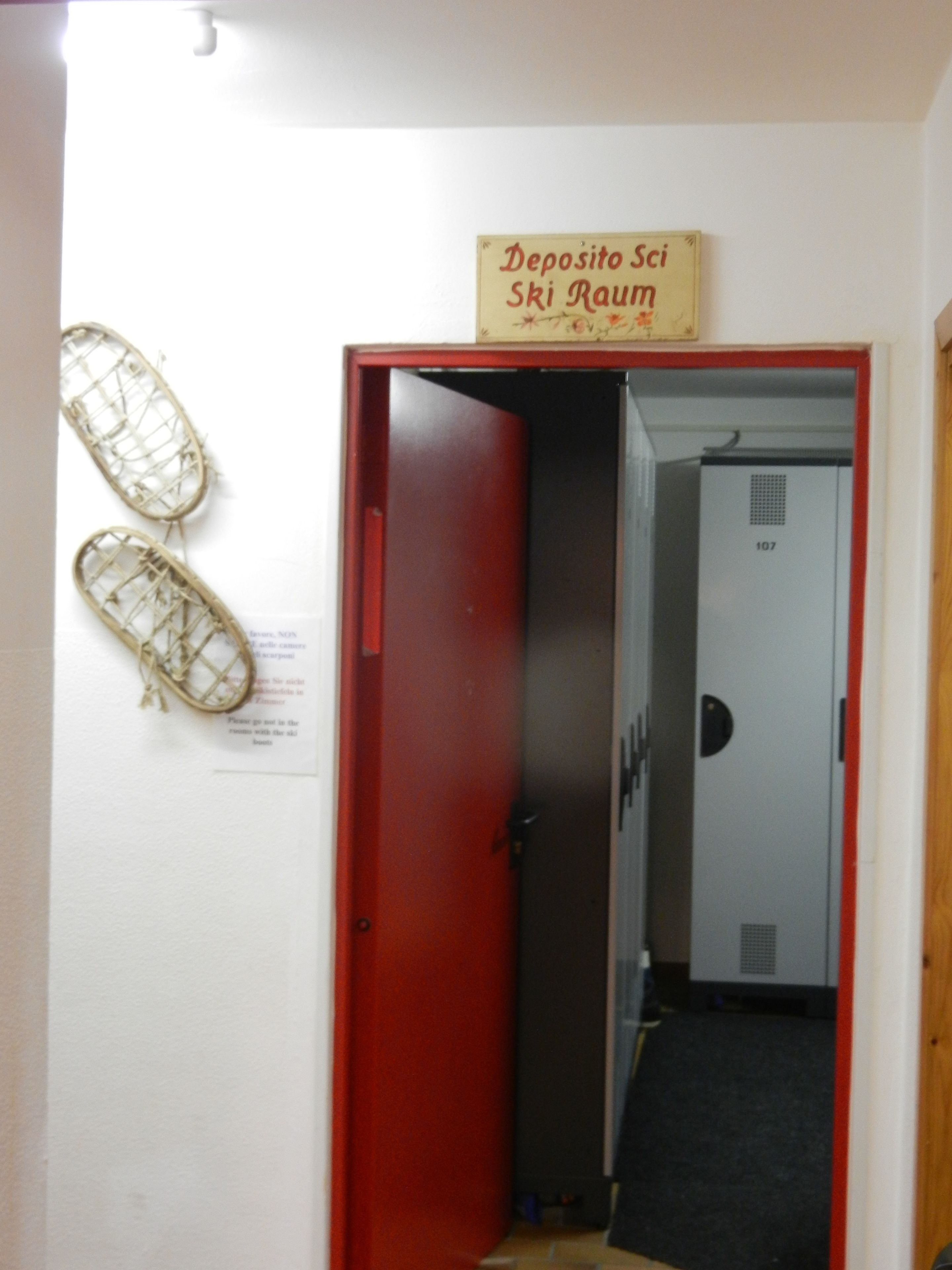 A door with a sign reading "Deposito Sci Ski Raum" and a pair of skis hanging on the wall.