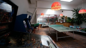 Une pièce équipée d’un baby-foot, d’une table de ping-pong et d’une grande fenêtre offrant une belle vue.