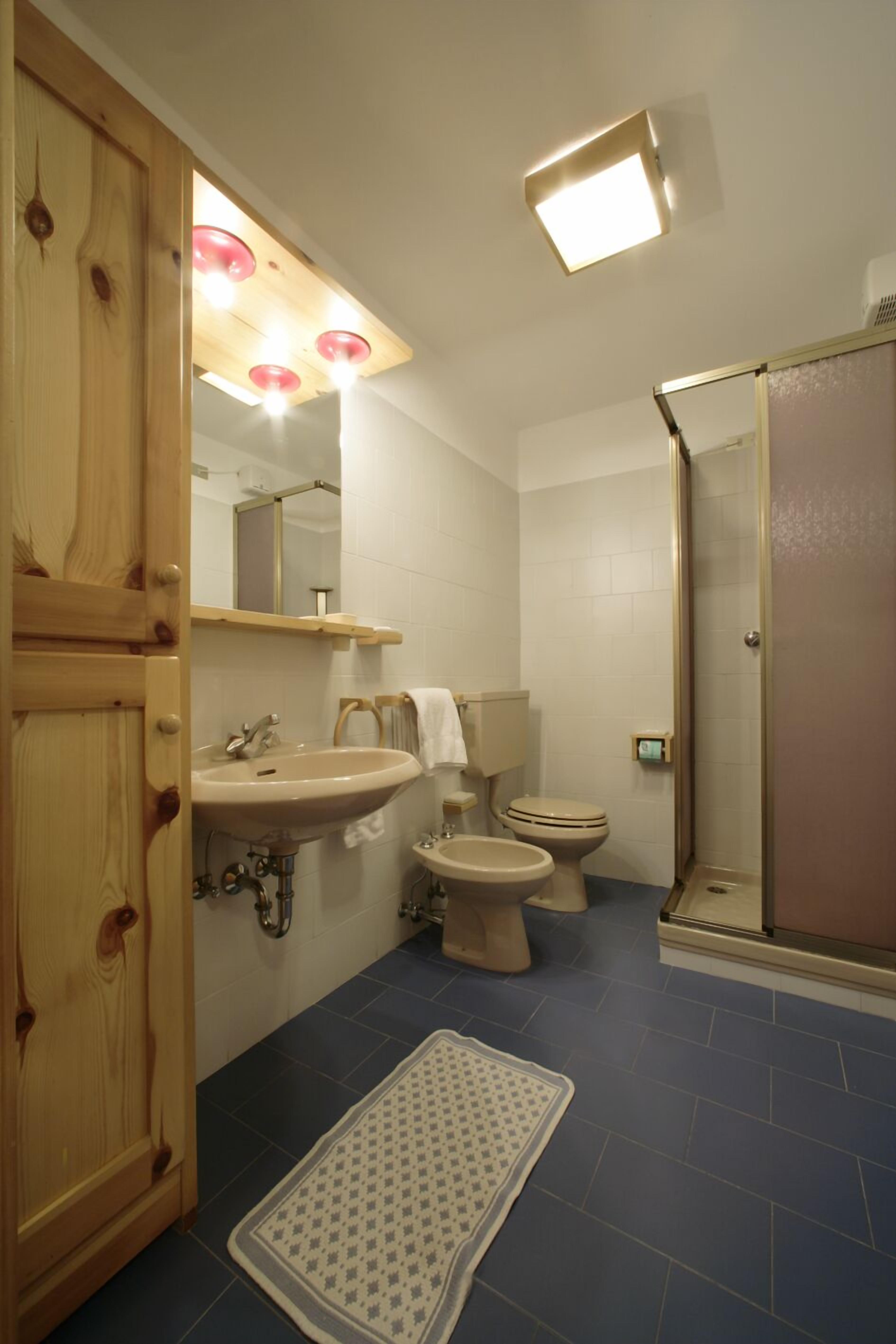 Ein Badezimmer mit Holzschrank, Waschbecken, Toilette, Bidet und Duschbereich.