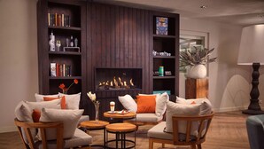A cozy living room with a fireplace, wooden furniture, and bookshelves. - Badhotel Renesse (Renesse)