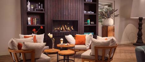 A cozy living room with a fireplace, wooden furniture, and bookshelves.
