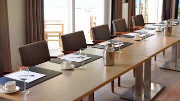 A conference room with a long table, multiple chairs, and a coffee pot.