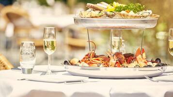 A seafood platter on a table with glasses of white wine and a bottle of water.