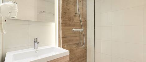 A modern bathroom with a wooden vanity, a white sink, and a glass shower enclosure.