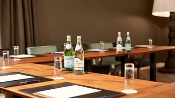 Een vergaderruimte met houten tafels, glazen en flesjes Pellegrino water.