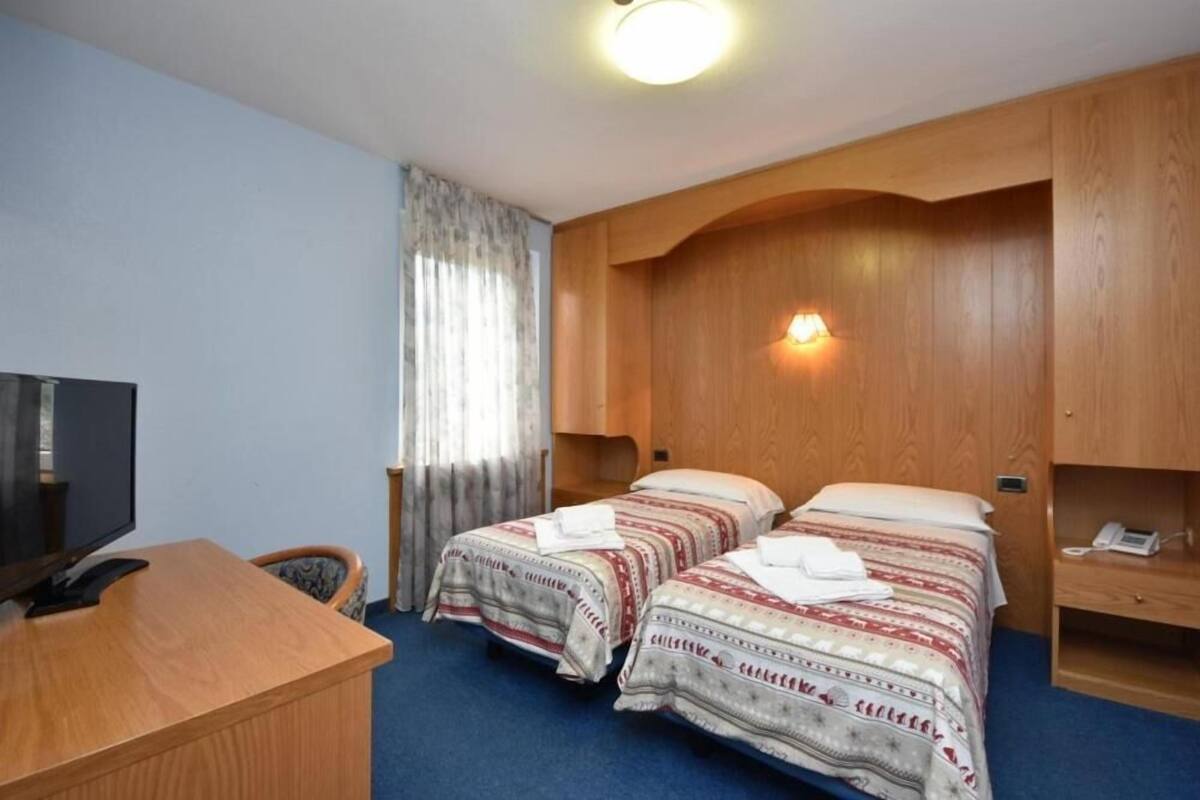 A hotel room with two beds, a desk, a television, and a telephone.
