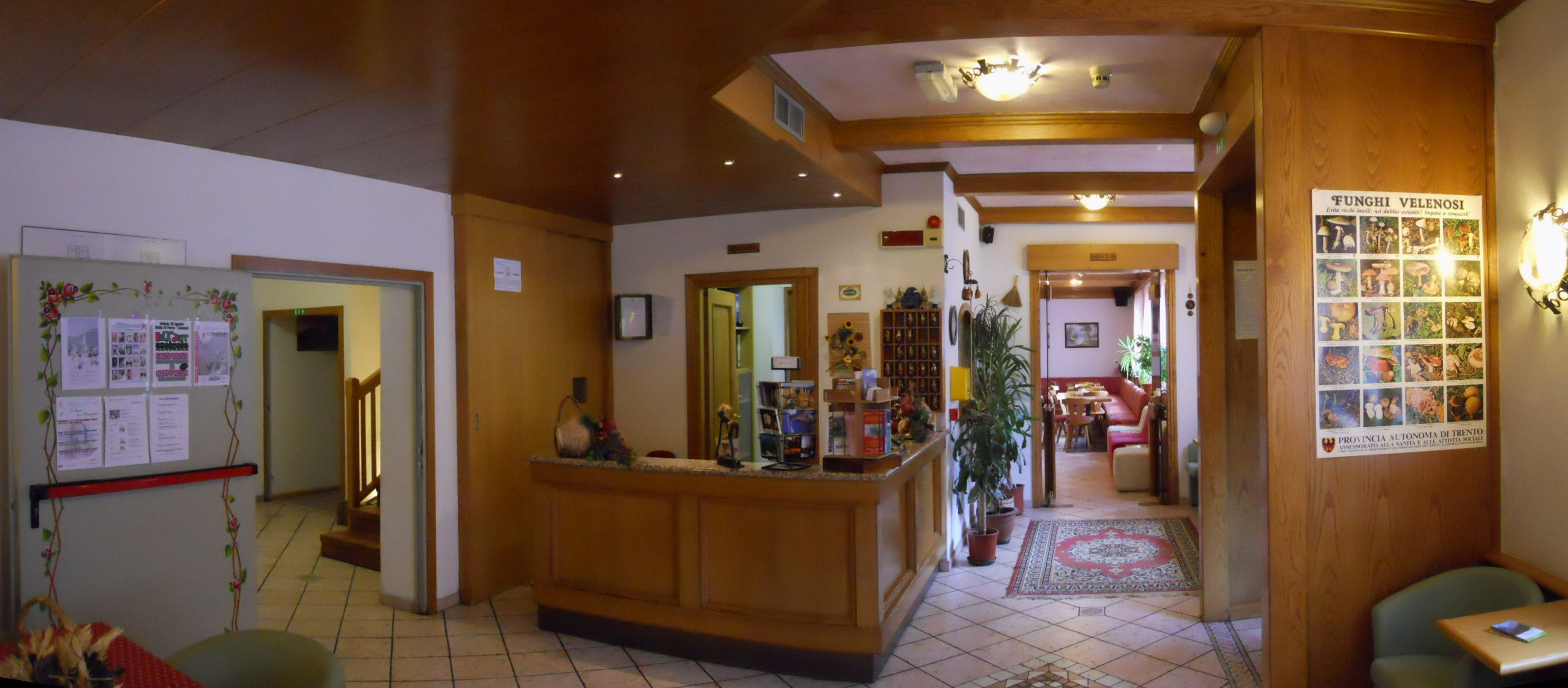 A reception area with a wooden reception desk, a whiteboard with notices, a refrigerator, and a wall with a poster.