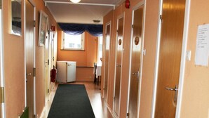 A hotel corridor with wooden floors, a carpeted walkway, and doors leading to rooms. - Barents Frokosthotell (South Varanger)