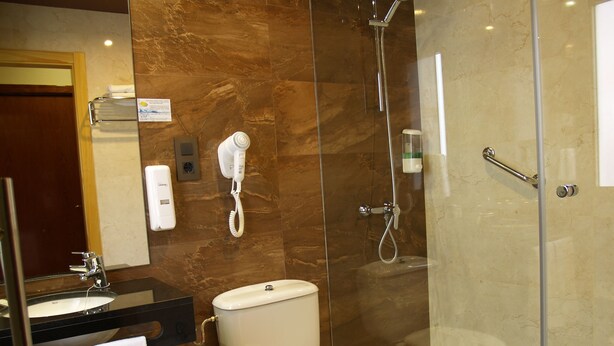 A modern bathroom with a glass-enclosed shower, a toilet, a sink with a mirror, and a towel rack. - Hotel Navarro (Ciudad Real)