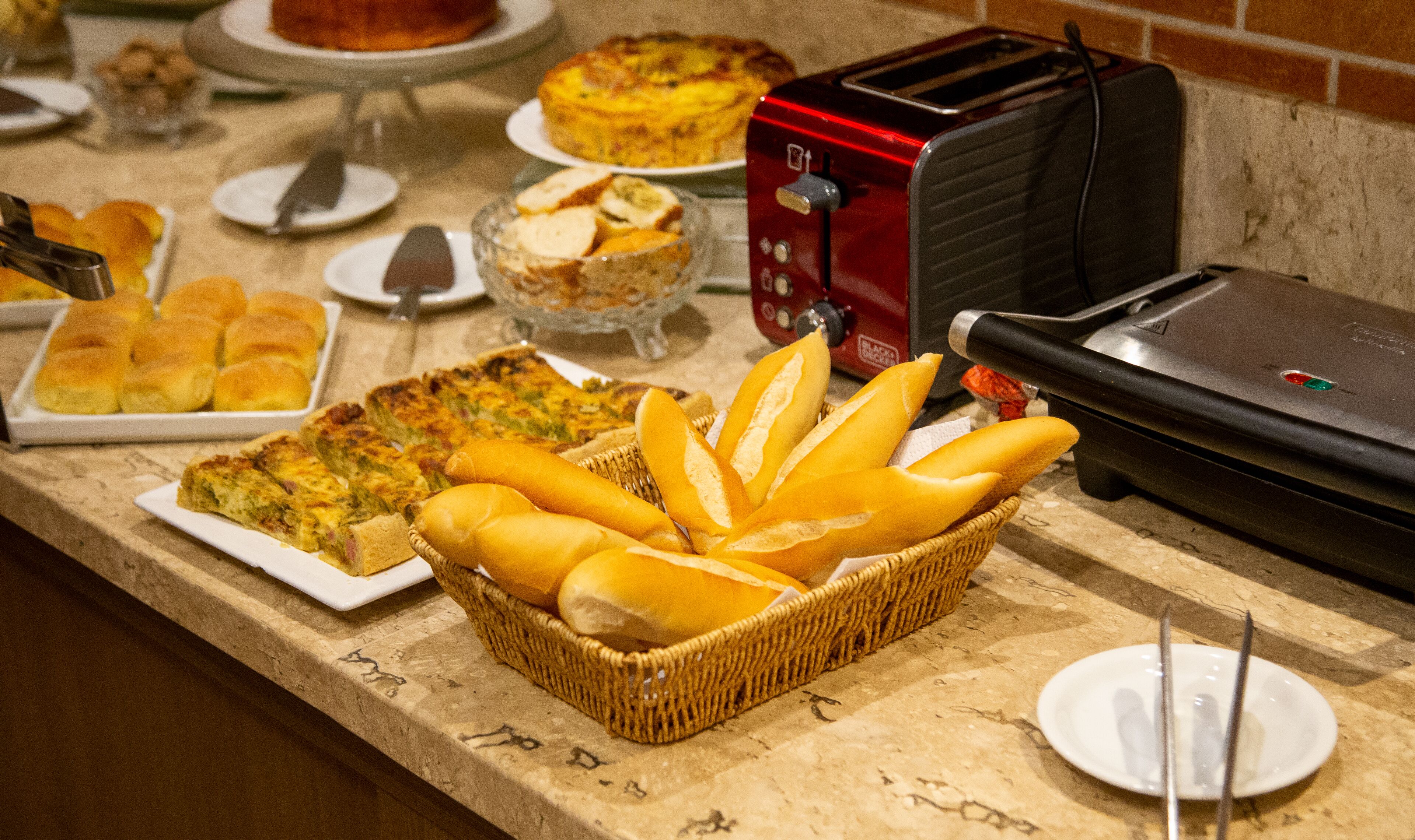 A buffet table with various food items including quiches, bread, and a toaster.