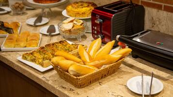 A buffet table with various food items including quiches, bread, and a toaster.