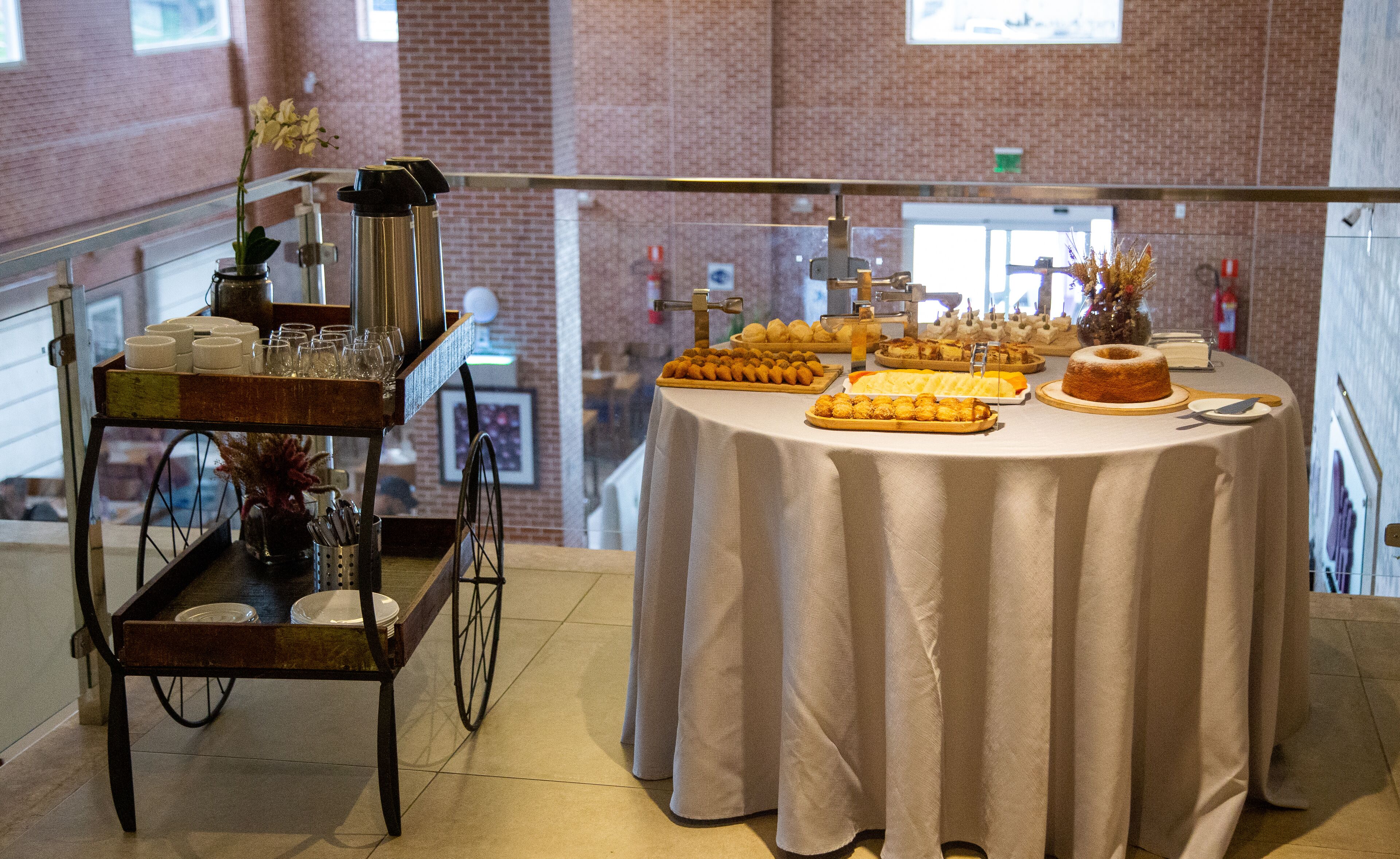 A buffet table with various food items and a cart with plates and glasses.