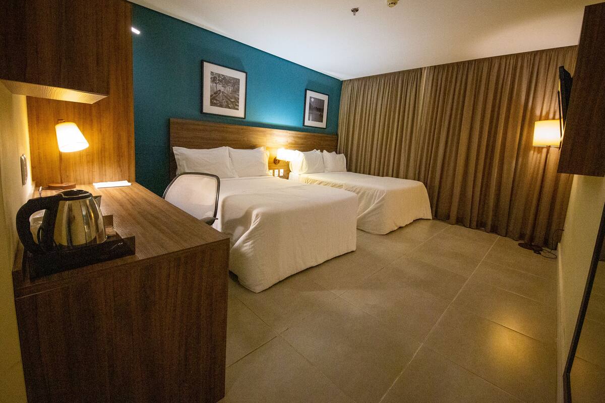 A hotel room with a bed, bedside tables, lamps, and a wooden headboard.