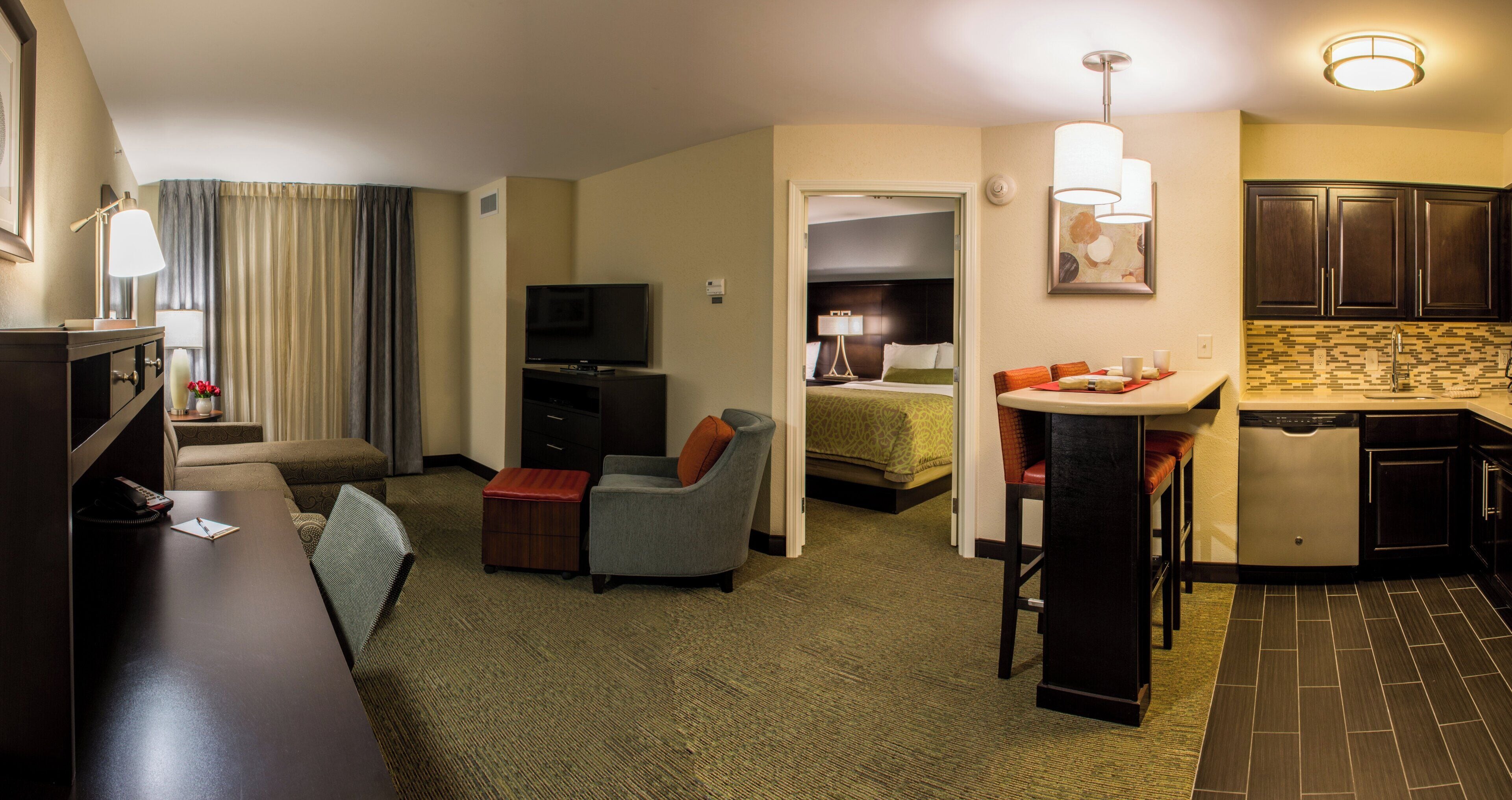 A hotel room with a living area, a separate bedroom, a kitchenette, and a bathroom.