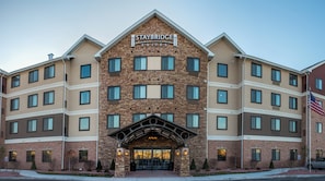 A Staybridge Suites hotel with a stone facade, multiple windows, and an American flag. - Staybridge Suites Schererville by IHG (Schererville)