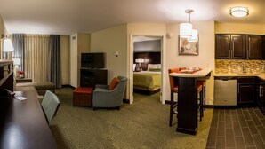 A hotel room with a desk, a chair, a sofa, a TV, a kitchenette, and a bathroom. - Staybridge Suites Schererville by IHG (Schererville)