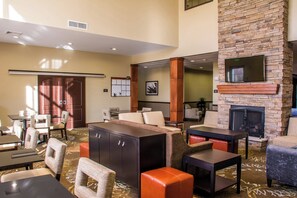 A hotel lobby with a fireplace, seating area, and a reception desk. - Staybridge Suites Schererville by IHG (Schererville)