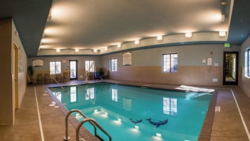Una piscina interior con agua cristalina, un puesto de socorrista y múltiples salidas.