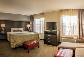 Habitación de hotel con una cama, televisor, escritorio y una silla.