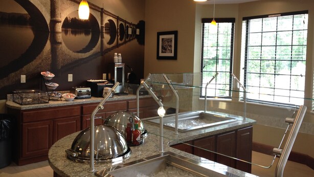 A kitchen with granite countertops, a stainless steel sink, and a large mural of a bridge. - Staybridge Suites Schererville by IHG (Schererville)