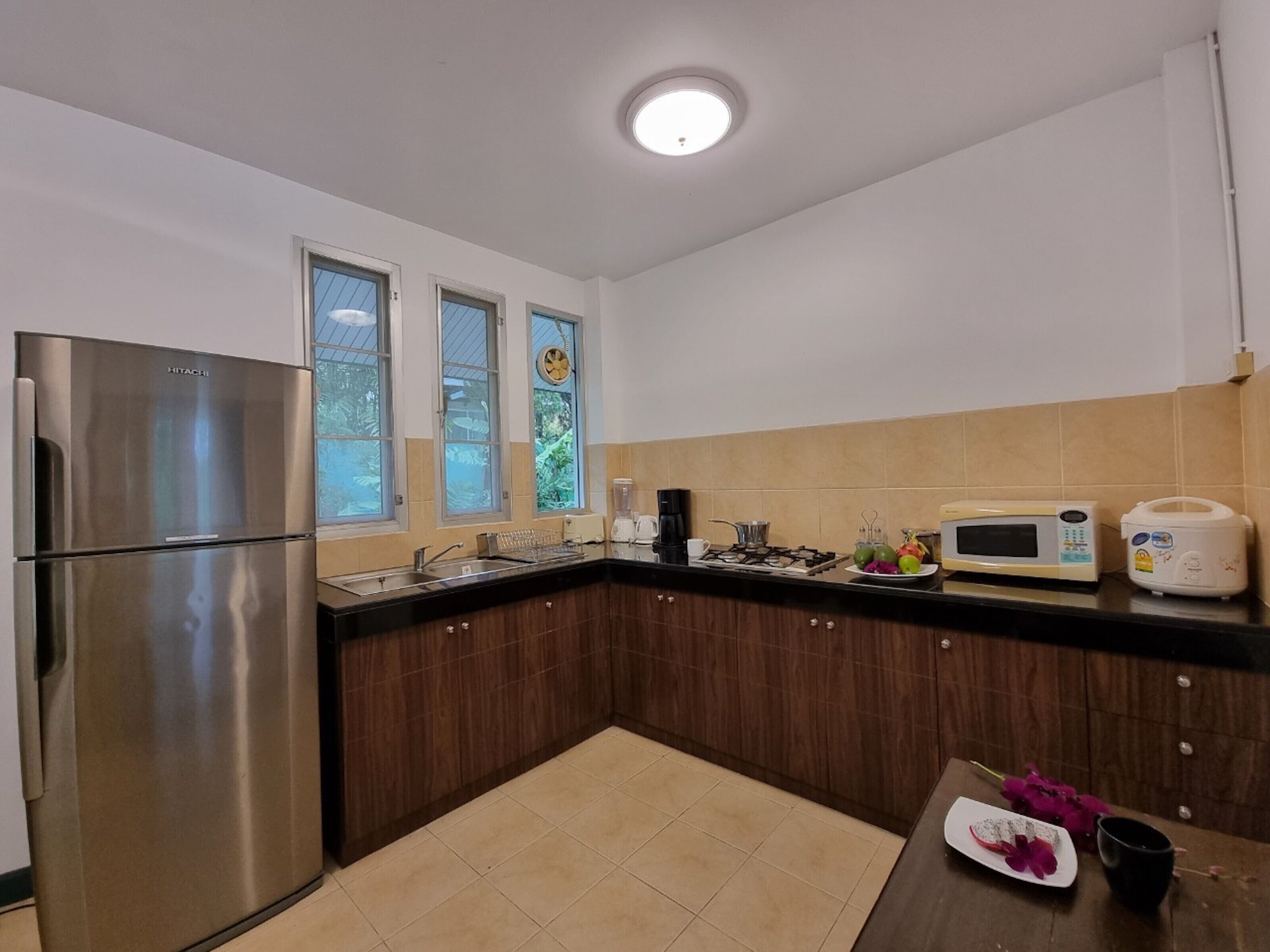 A modern kitchen with stainless steel appliances, a black countertop, and a window with a view of greenery.