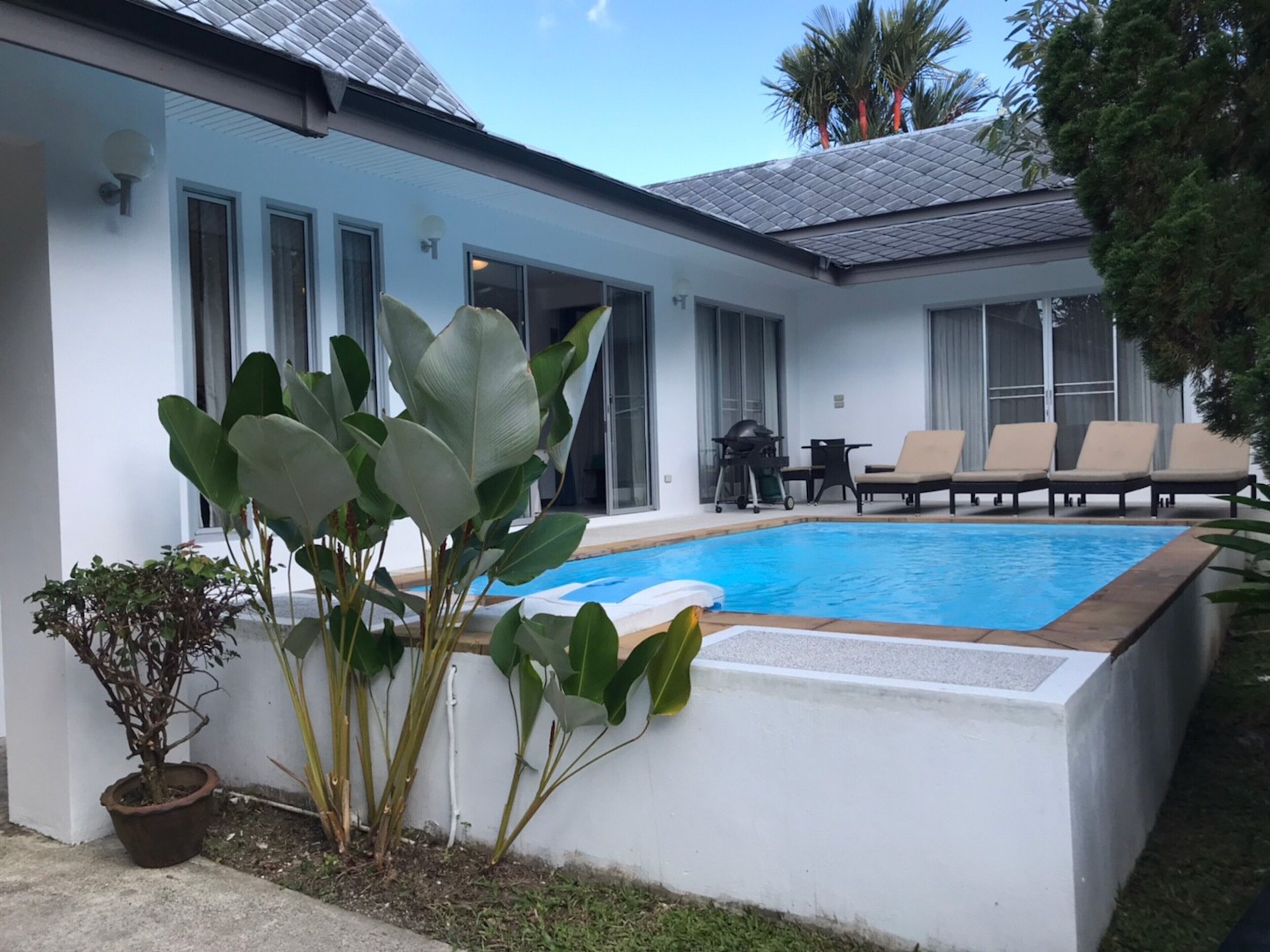 A modern house with a swimming pool, outdoor seating, and large windows.