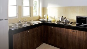 A modern kitchen with a refrigerator, double sink, wooden cabinets, and a stove. - Baan Gecko (Krabi)