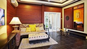 A bedroom with a bed, bedside table, lamp, and a chair. - Baan Manu Chang (Krabi)