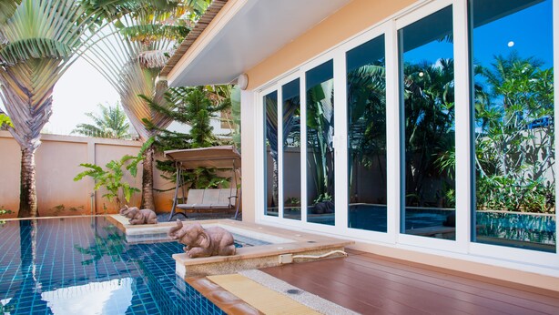 A modern pool area with a clear view of the pool, a wooden deck, and surrounding tropical plants. - Baan Manu Chang (Krabi)