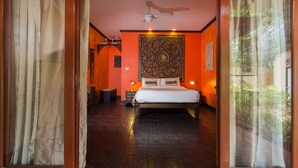 A bedroom with a bed, a ceiling fan, and a large tapestry on the wall. - Baan Manu Chang (Krabi)