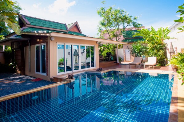 A modern house with a swimming pool, large windows, and a covered patio area.