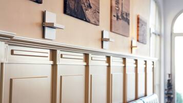 A hallway with a cream-colored wall, a radiator, and framed artwork.
