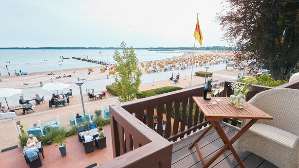 Une terrasse avec des sièges extérieurs donnant sur une plage.