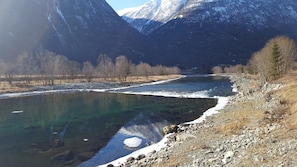 Een heldere rivier met rotsachtige oevers en besneeuwde bergen op de achtergrond.