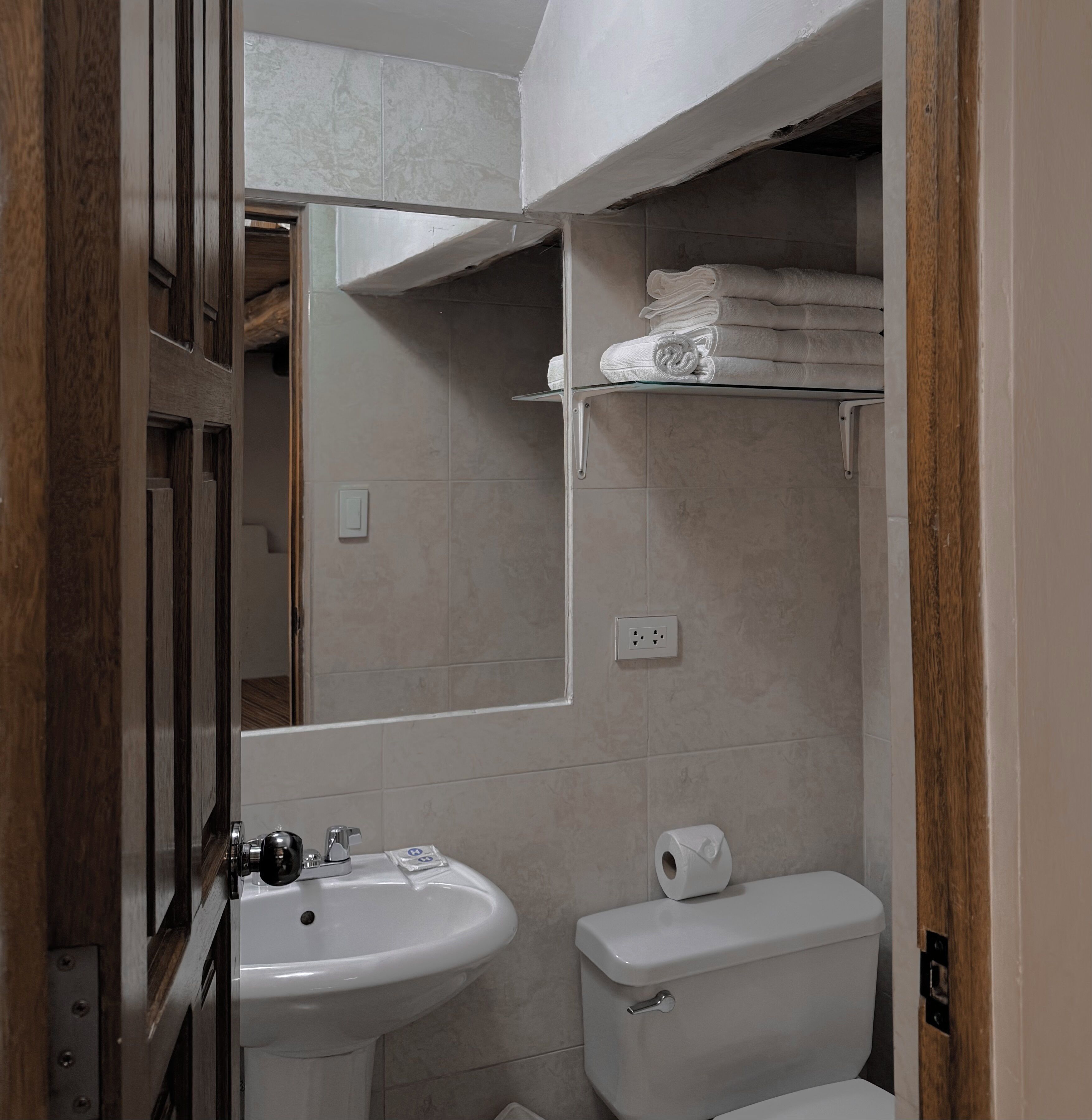 A compact bathroom with a sink, toilet, and a mirror.