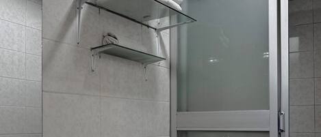 A bathroom with a toilet, a bidet, a glass shower enclosure, and a towel rack.