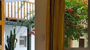 A room with a bed, a window with curtains, a view of a balcony with plants, and a door leading outside. - Huascaran Casa Boutique Cusco (Cusco)