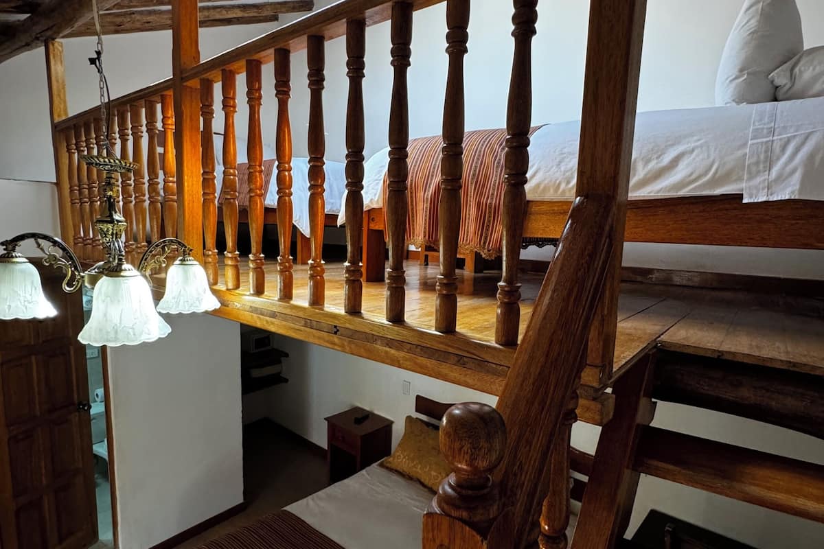 Escada de madeira em vários níveis com uma cama no andar superior.