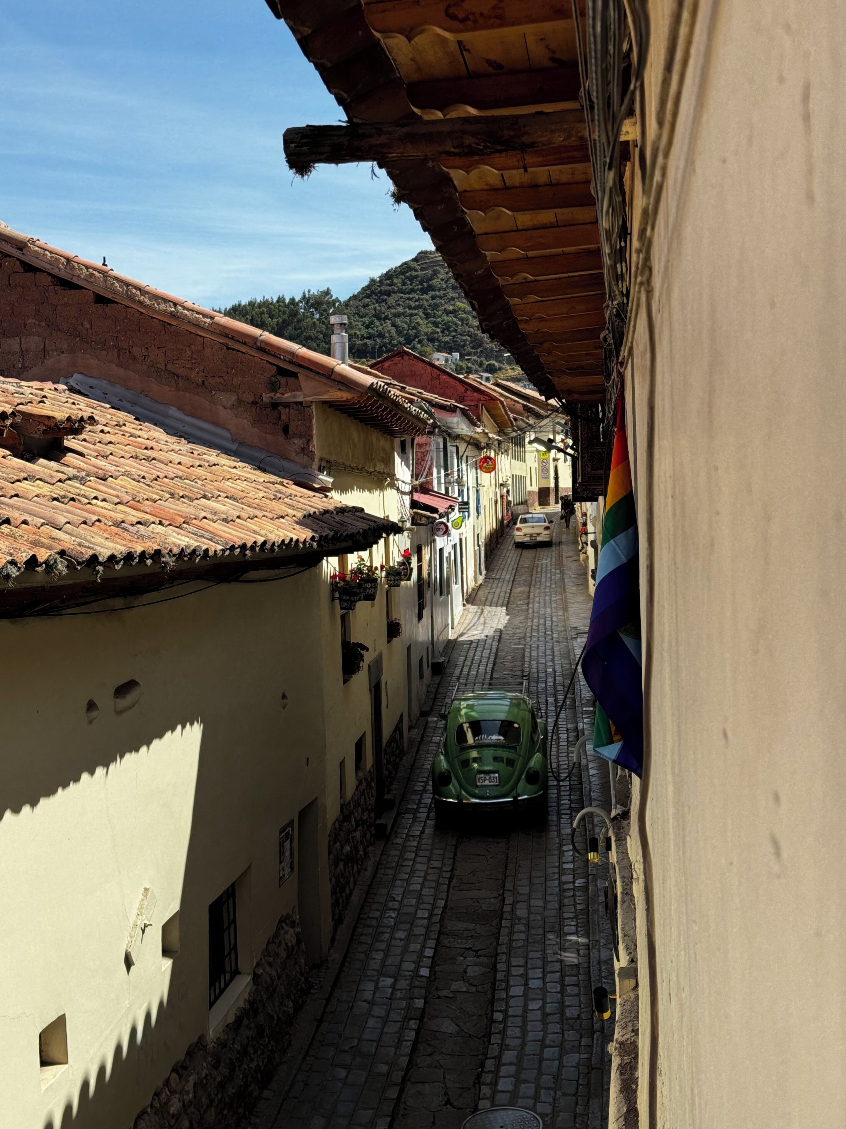A narrow cobblestone street flanked by traditional buildings with terracotta roofs and white walls.