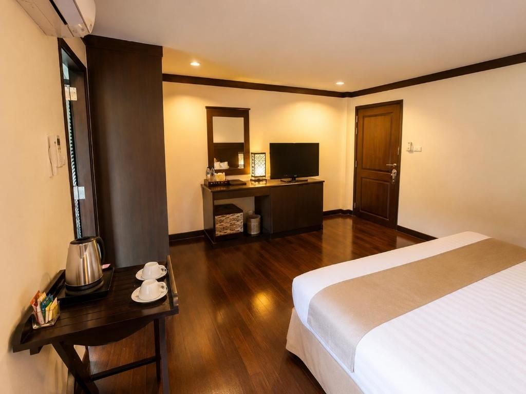 A hotel room with a bed, a desk with a coffee maker, a television, and a wardrobe.