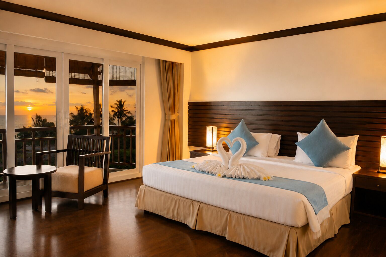 Habitación de hotel con una cama, una silla, una mesita de noche, una lámpara y vistas a la puesta de sol a través de las puertas del balcón.