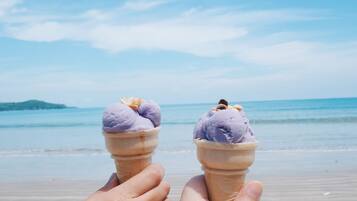 Dos helados en una playa, con un cielo despejado y un mar tranquilo al fondo.