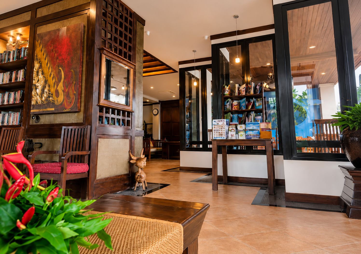 A hotel lobby with a wooden reception desk, a bookshelf, and a large painting.