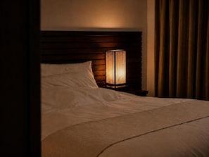 Un lit avec une tête de lit, une lampe de chevet et un rideau.