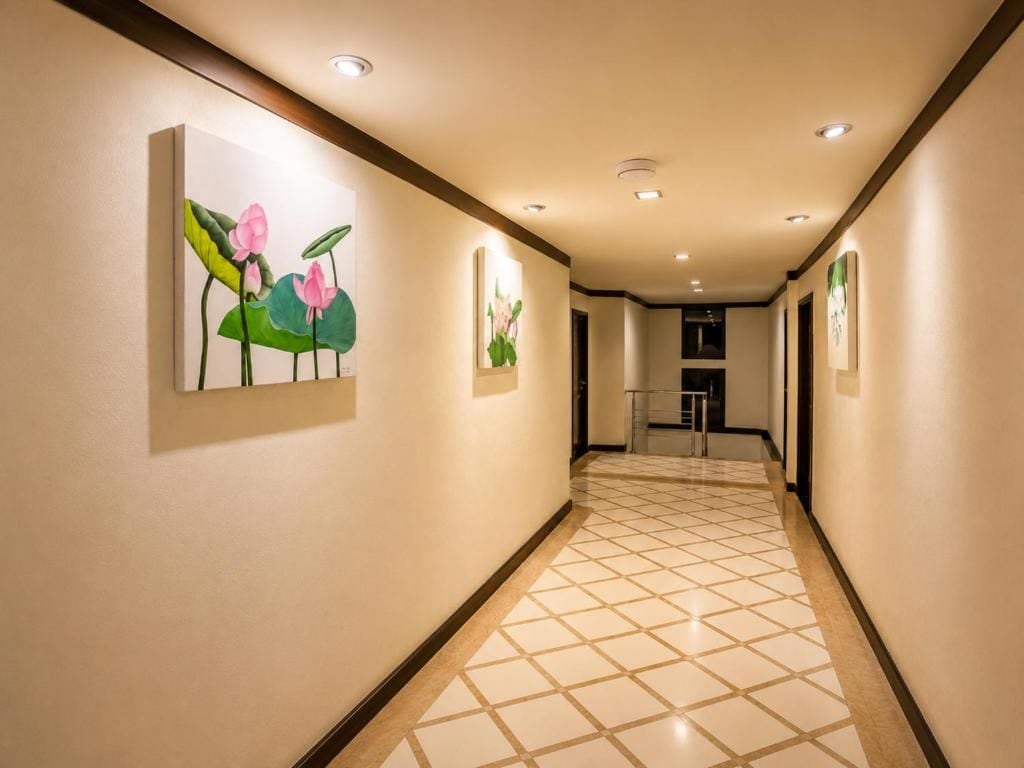 A hotel hallway with artwork on the walls, a tiled floor, and a staircase at the end.