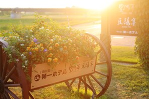 A flower cart with a sign in Japanese, located outdoors with a bridge in the background. - Tokachigawa Onsen Daiichi Hotel Hoshutei Toyotei (Otofuke)