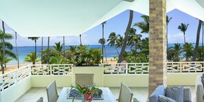 A balcony with a view of the beach and ocean, wicker furniture, and a table with a vase of flowers. - Hotel Residence Marilar (Las Terrenas)