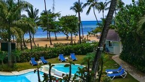 Área da piscina com espreguiçadeiras e vista para a praia.
