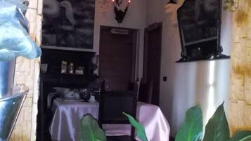 Un coin repas chaleureux, agrémenté d’un lustre, d’une tête de cerf accrochée au mur et d’une fenêtre donnant sur l’extérieur.